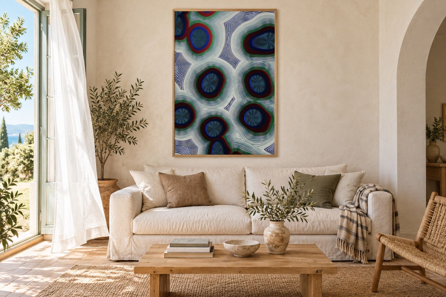 Large blue and red Cristaux poster above a white sofa in a sunlit Mediterranean room